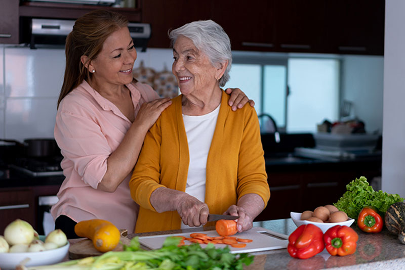 happy cargiver and senior lady cooking